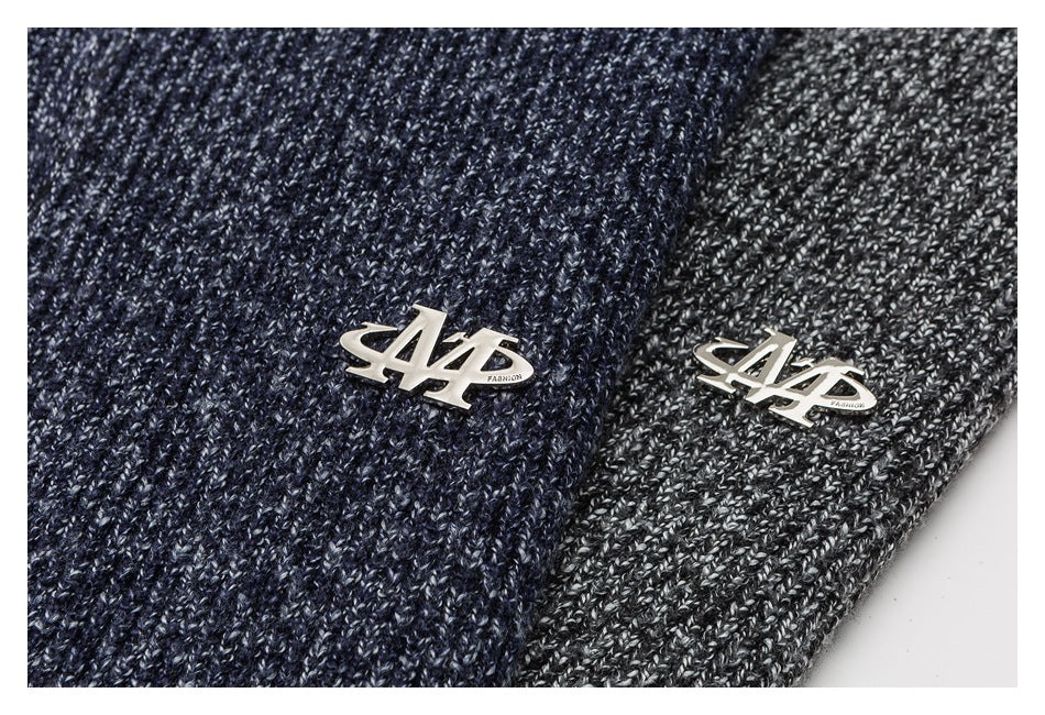 Close-up of metal chest badges on navy and charcoal marled knit fabric.
