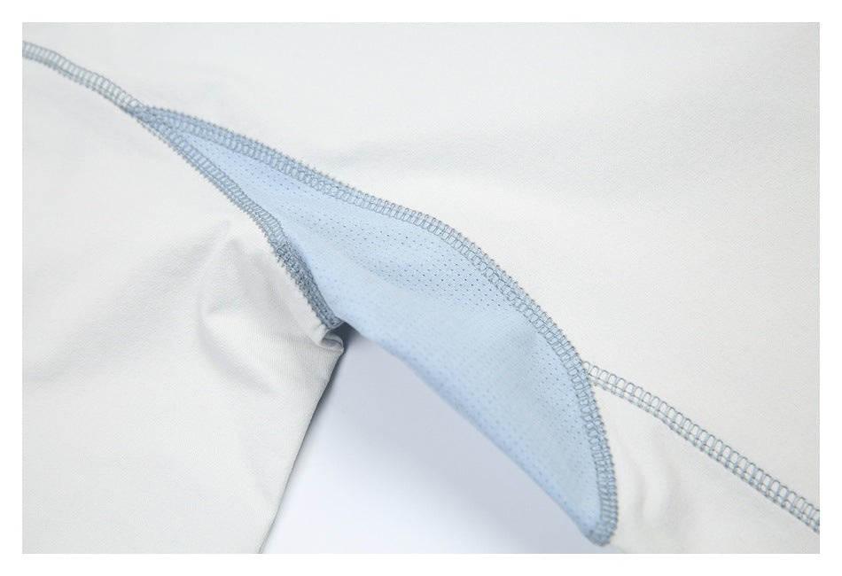 Inside view of an off-white garment seam with a pale blue mesh insert and overlock stitching.