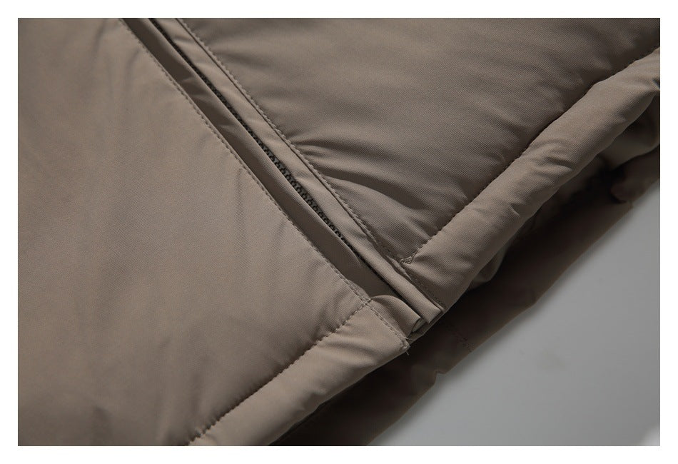 Close-up of a taupe padded garment showing a diagonal zipper, stitched seams, and a quilted section.