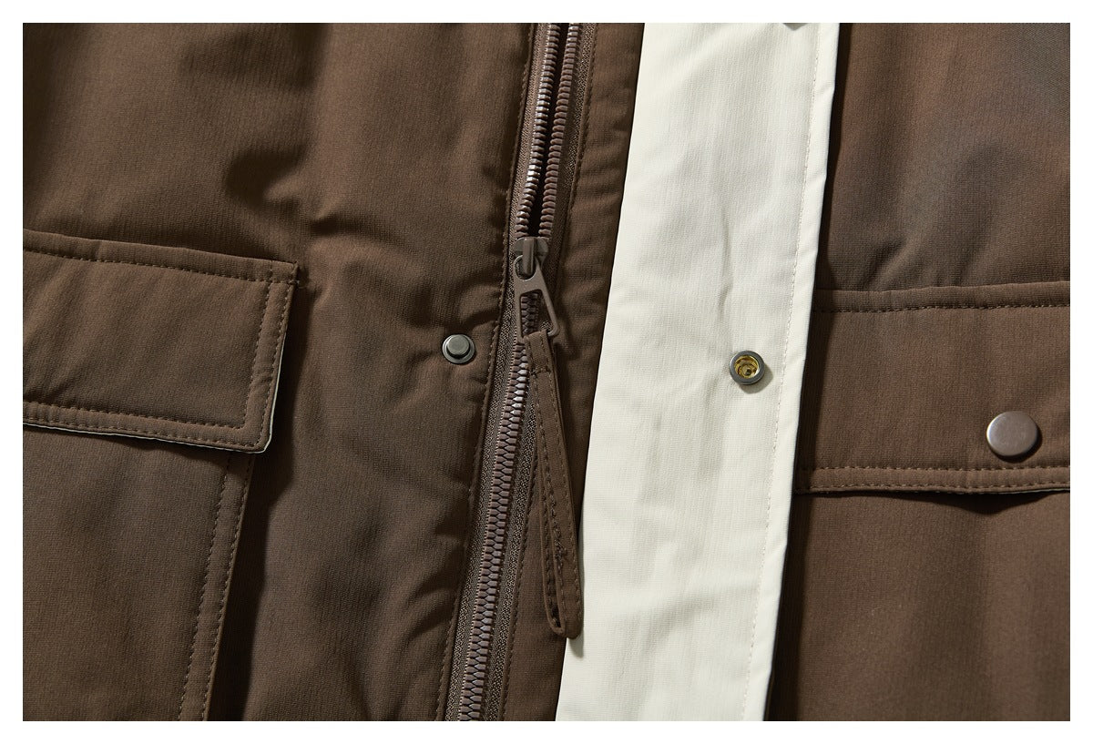Close-up of a brown jacket's front zipper, snap-button storm flap, and large flap pockets.