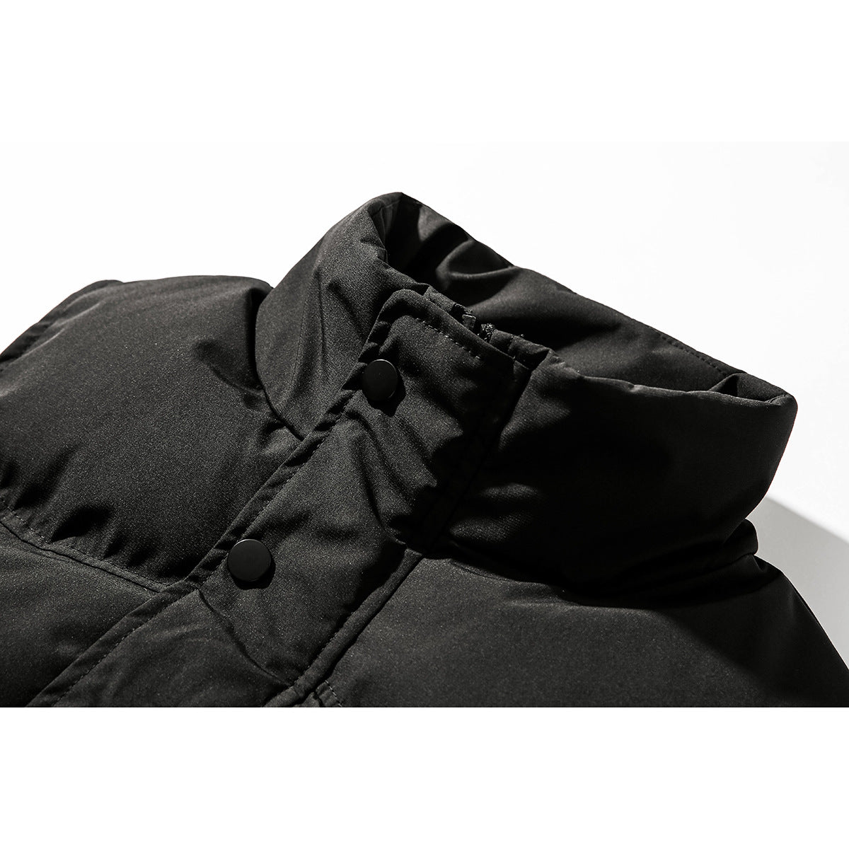 Close-up of a black jacket’s tall collar and snap-button front placket.