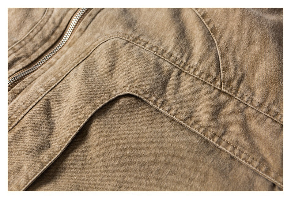 Close-up of a tan garment showing a metal zipper, curved seams, and mottled fabric.