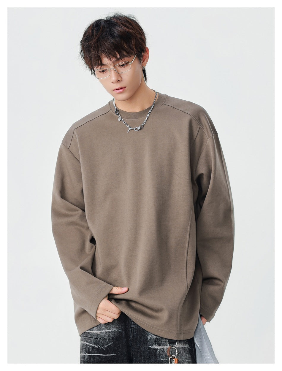 Man wearing a brown long-sleeve crewneck top with a relaxed fit, looking down