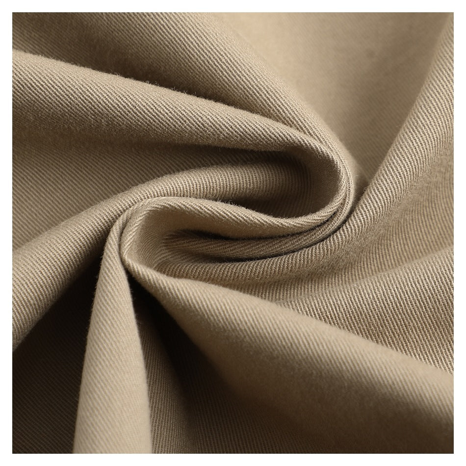 Macro view of taupe trouser fabric folded to show its diagonal weave and texture.