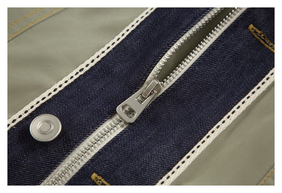 Close-up of a metal zipper and snap on a dark denim panel edged with white trim.