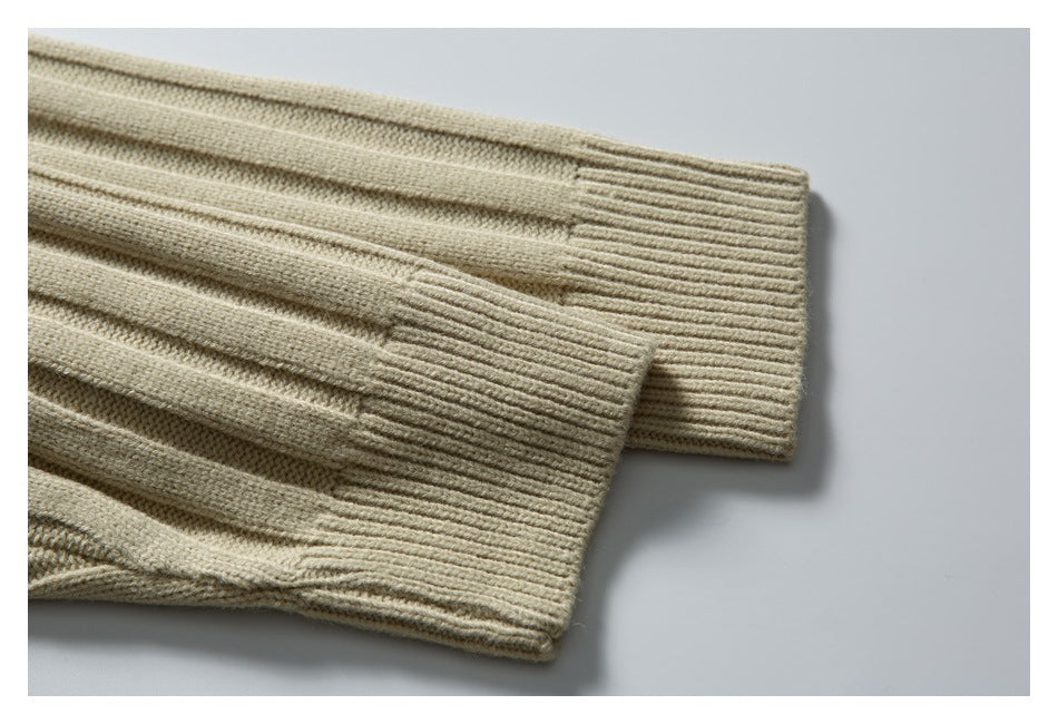 Close-up of two beige sweater sleeve cuffs with vertical ribbing and knit texture.