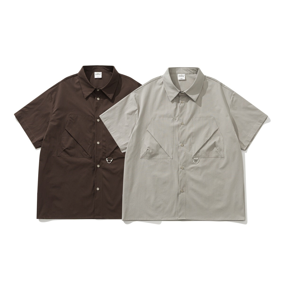 Two short-sleeve button-up shirts shown from the front in dark brown and light gray, each with angular chest pockets.