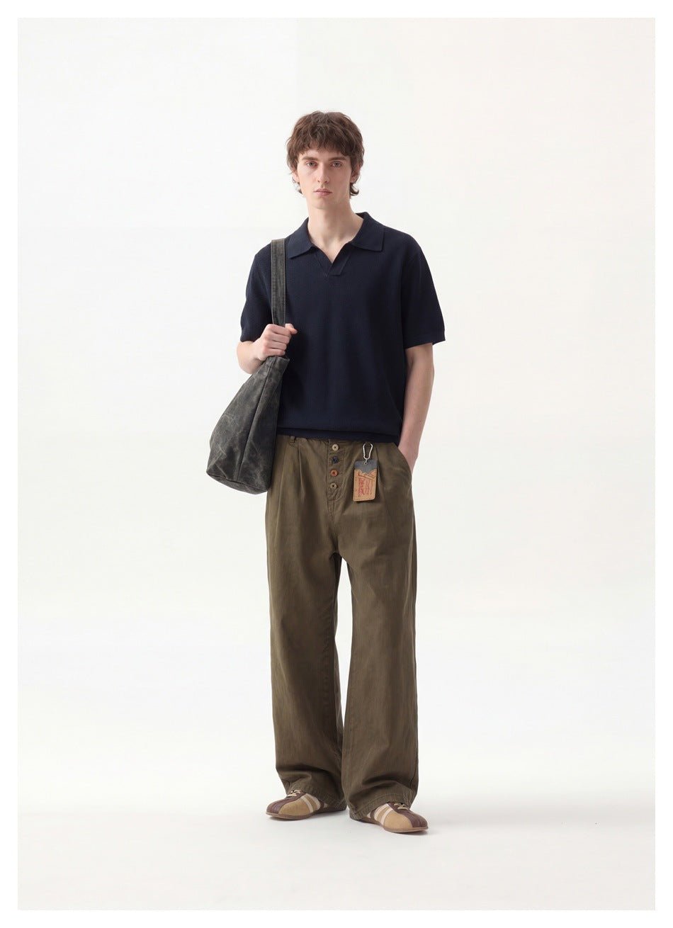 Man modeling a dark navy short-sleeve polo with olive wide-leg trousers and a shoulder bag.