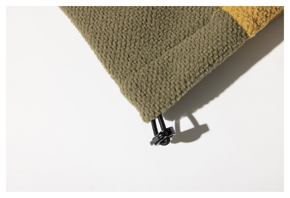 Close-up of an olive jacket hem with a black elastic drawcord toggle.