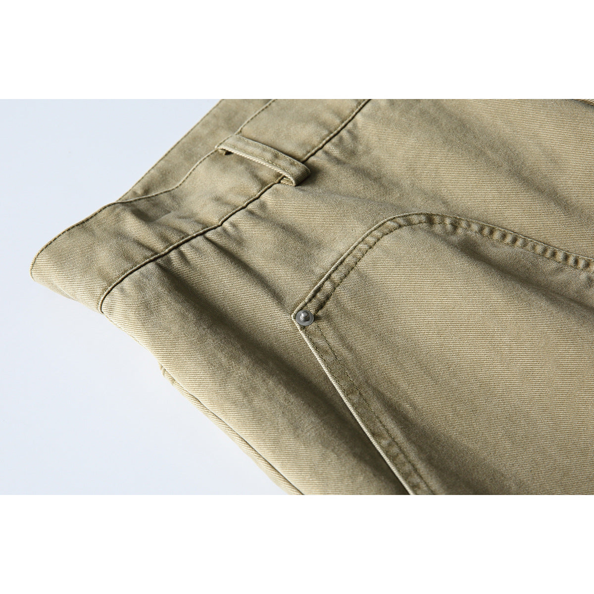 Close-up of khaki pants showing a belt loop, waistband stitching, and curved front pocket.