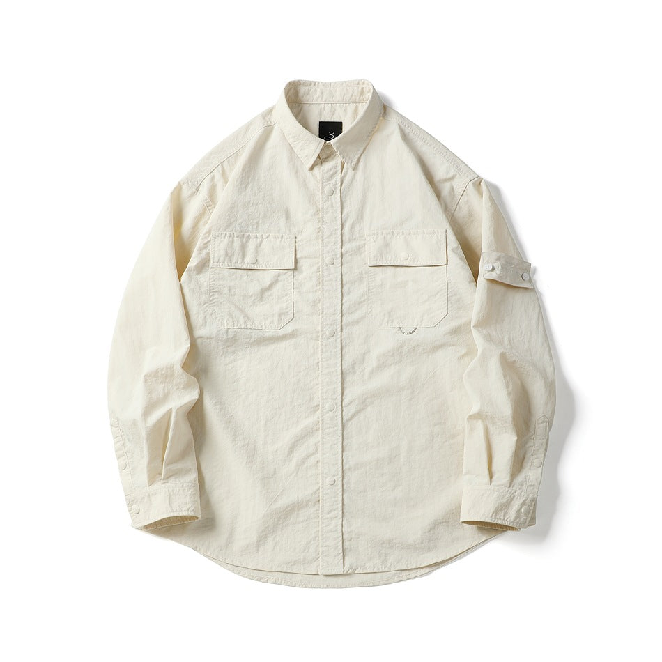 Off-white long-sleeve utility shirt with two flap chest pockets, snap placket and sleeve strap, flat lay front view