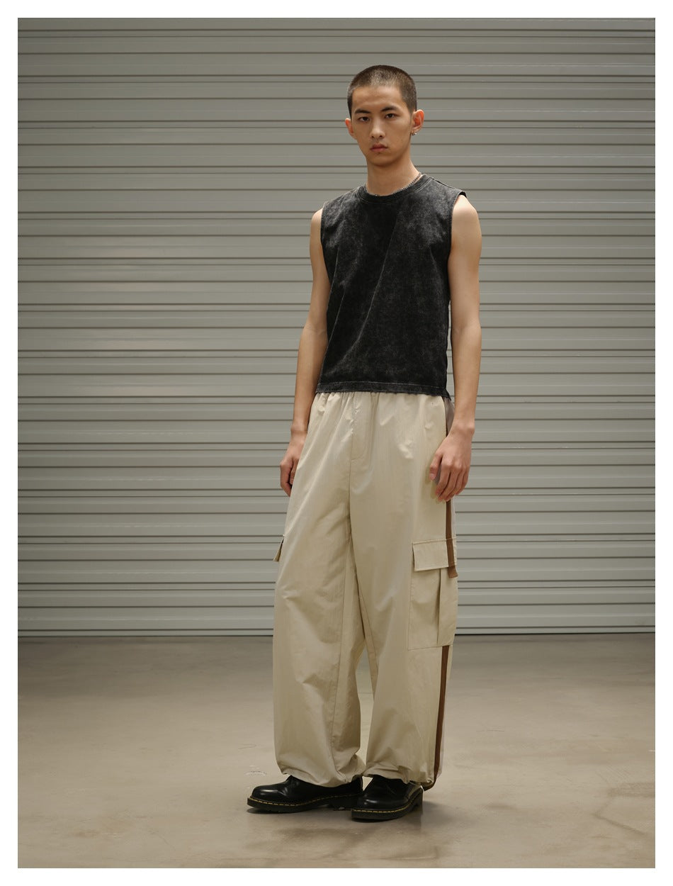 Front three-quarter view of a model wearing a black sleeveless top and loose beige cargo pants.
