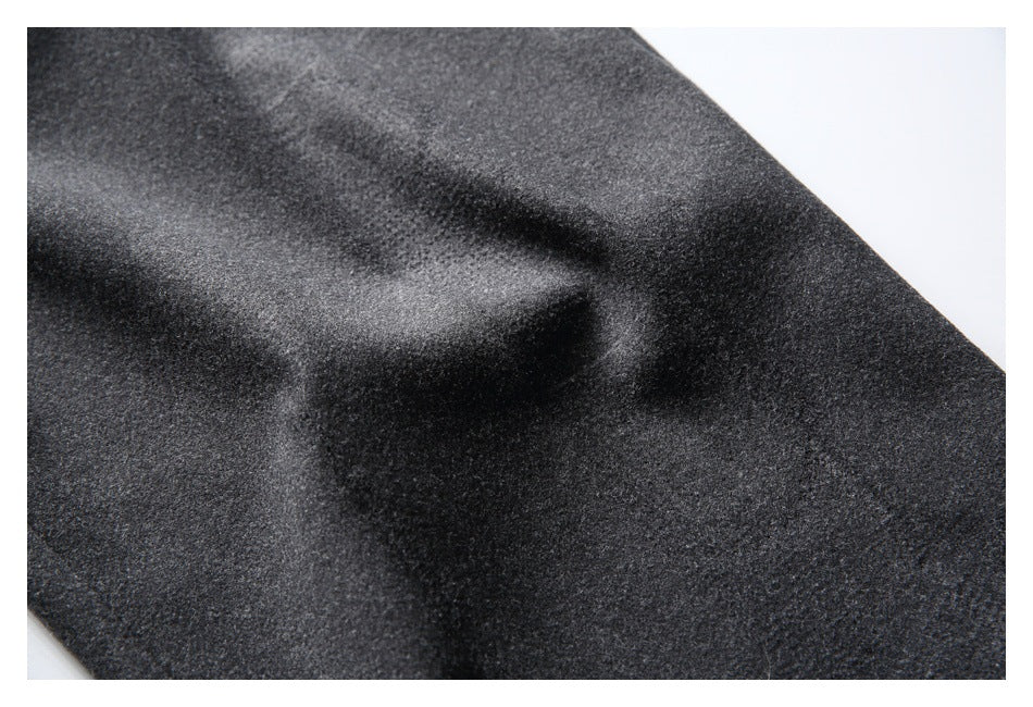 Close-up of charcoal gray trouser fabric with a soft fold and subtle surface texture.