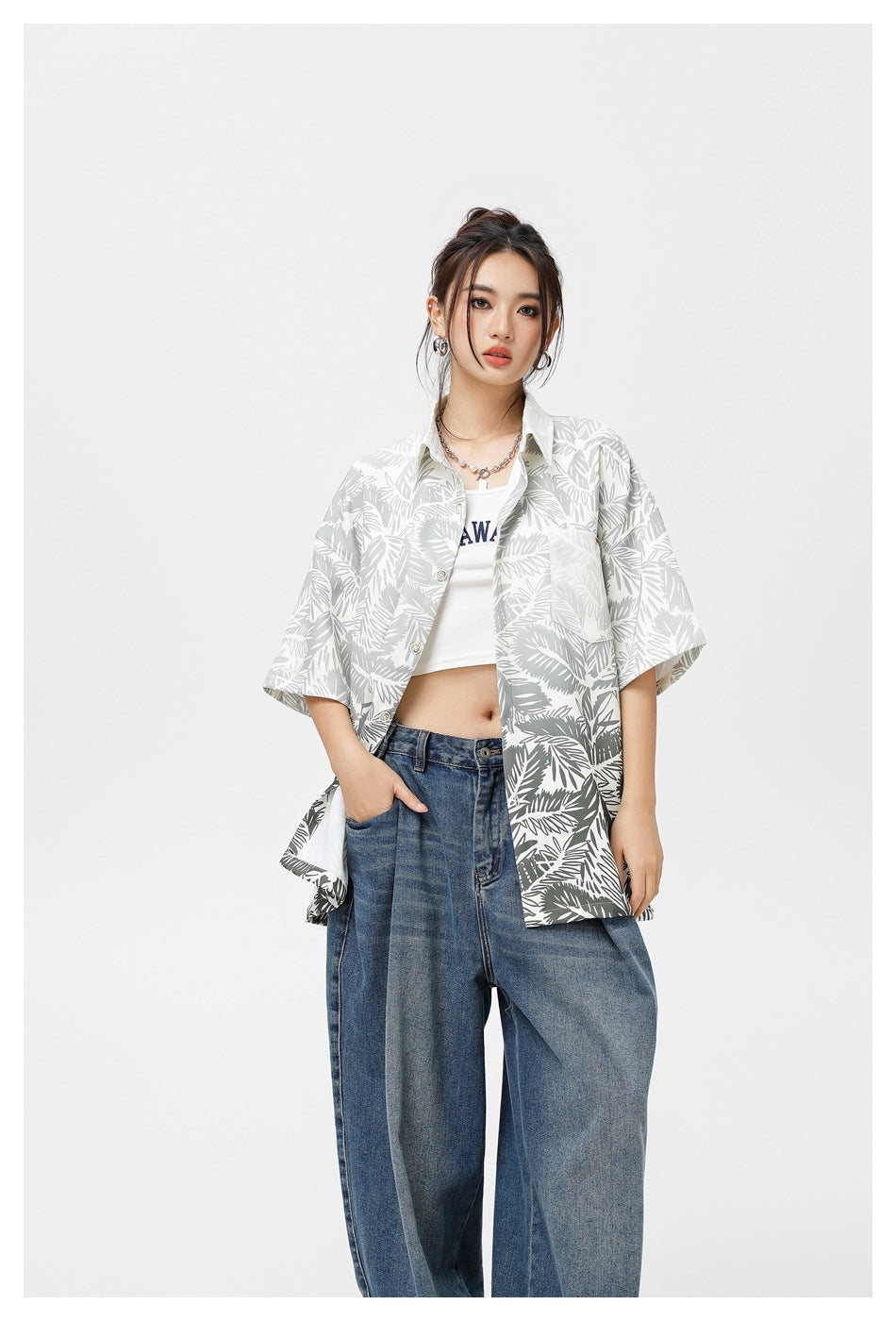 Woman wearing the gray leaf-print short-sleeve shirt open over a white crop top and wide-leg jeans