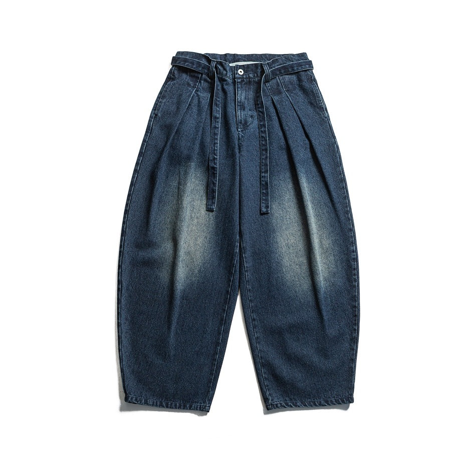 Navy blue faded wide-leg pleated jeans with a tie belt, flat lay front view