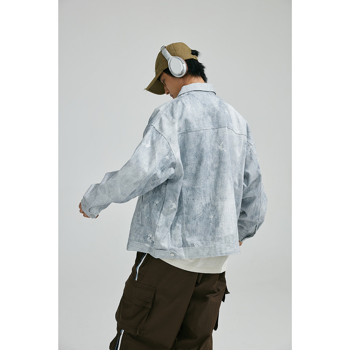 Model viewed from behind wearing a light gray mottled jacket with a wide back yoke and buttoned hem tabs.