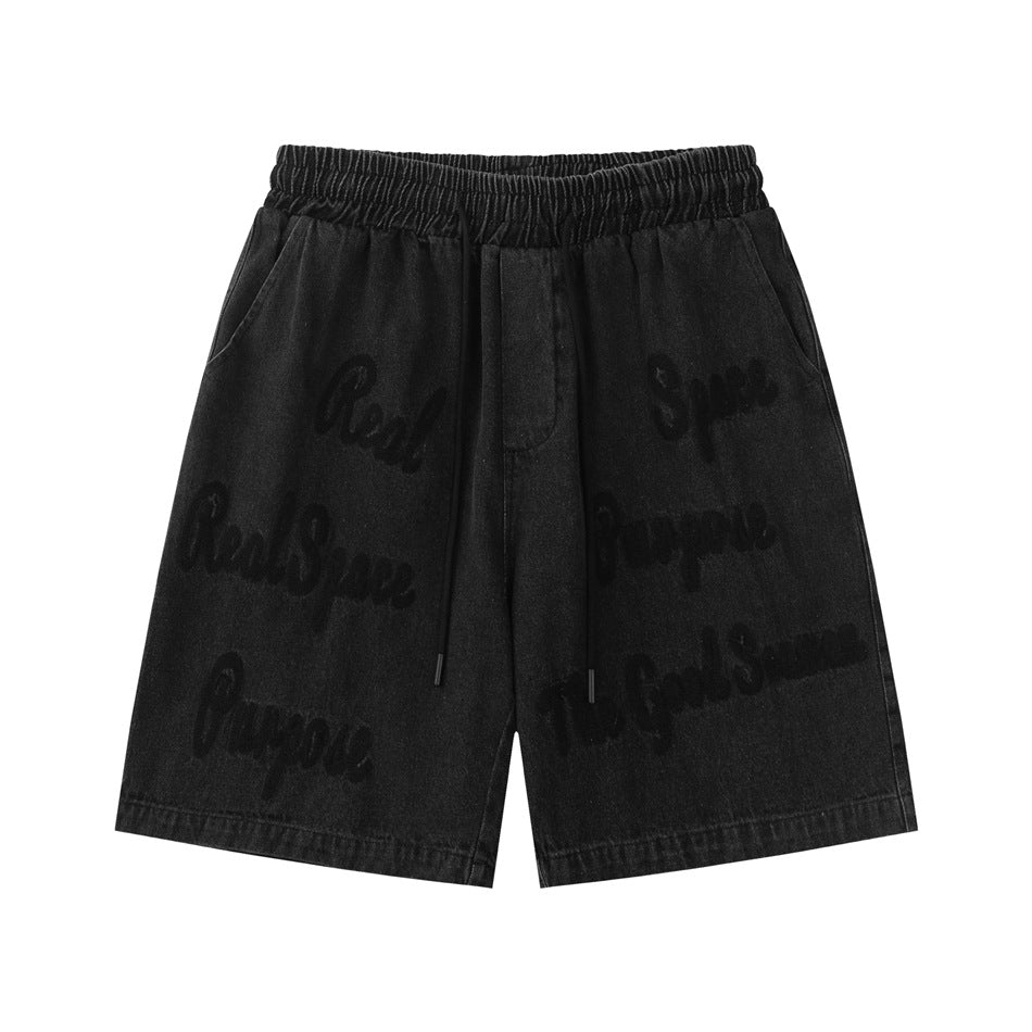 Washed black denim shorts with elastic drawstring waist and tone-on-tone script lettering on the front
