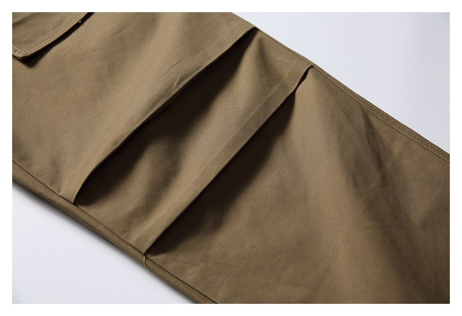Close-up of khaki trouser leg panels with layered seams and a stitched edge.