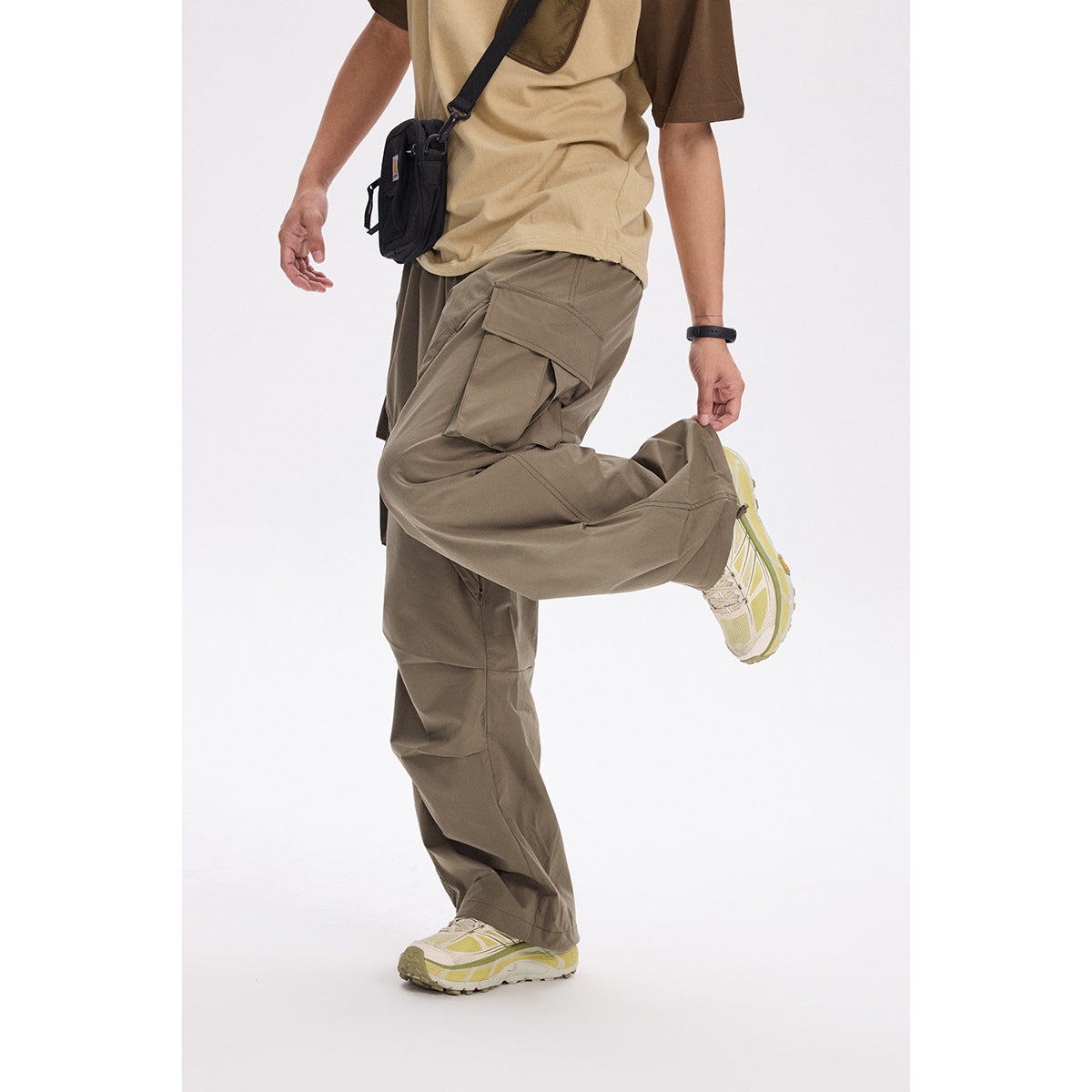 Model wearing loose taupe cargo pants with large flap pockets, paired with a tan-and-brown shirt.