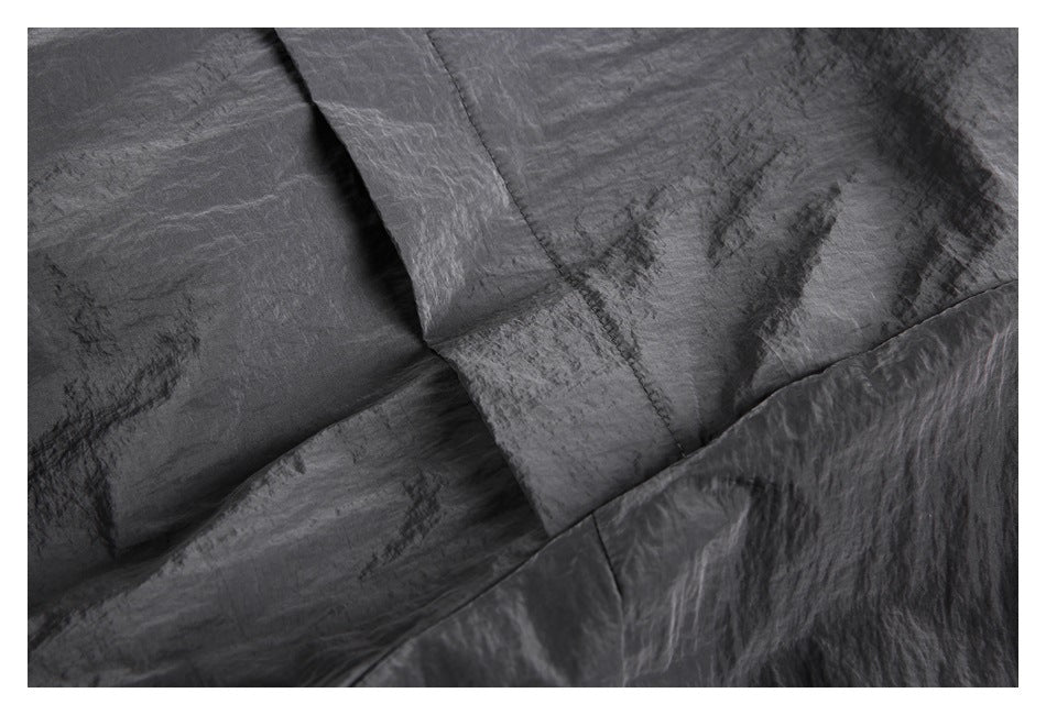 Close-up of dark charcoal garment panels with visible seams and a folded edge.