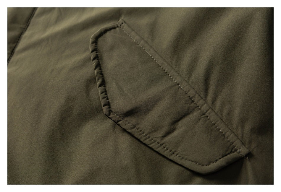 Close-up of a stitched flap pocket on an olive jacket.
