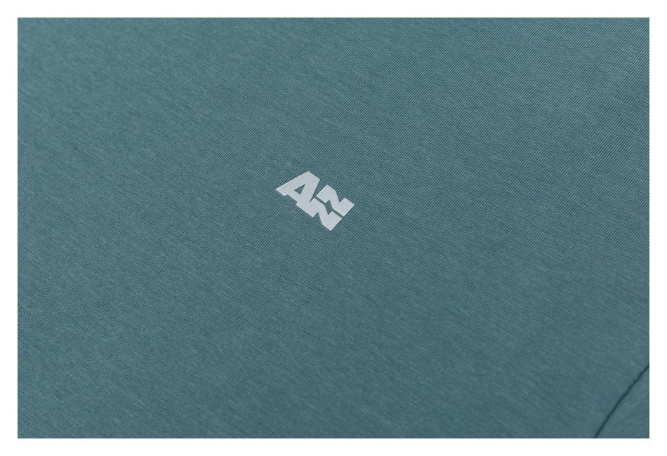 Close-up of a small white stylized logo printed on teal fabric.