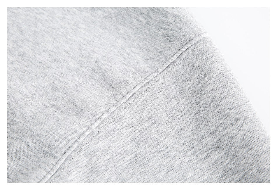 Close-up of a curved shoulder seam on light heather-gray sweatshirt fabric.
