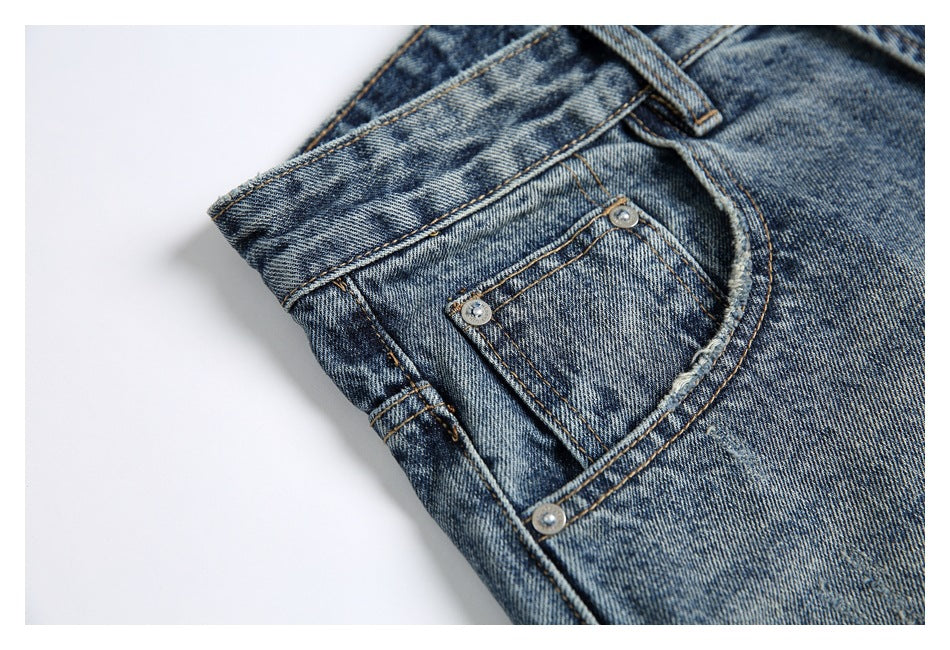 Close-up of the front coin pocket, rivets, belt loop, and contrast stitching on blue acid-wash jeans.