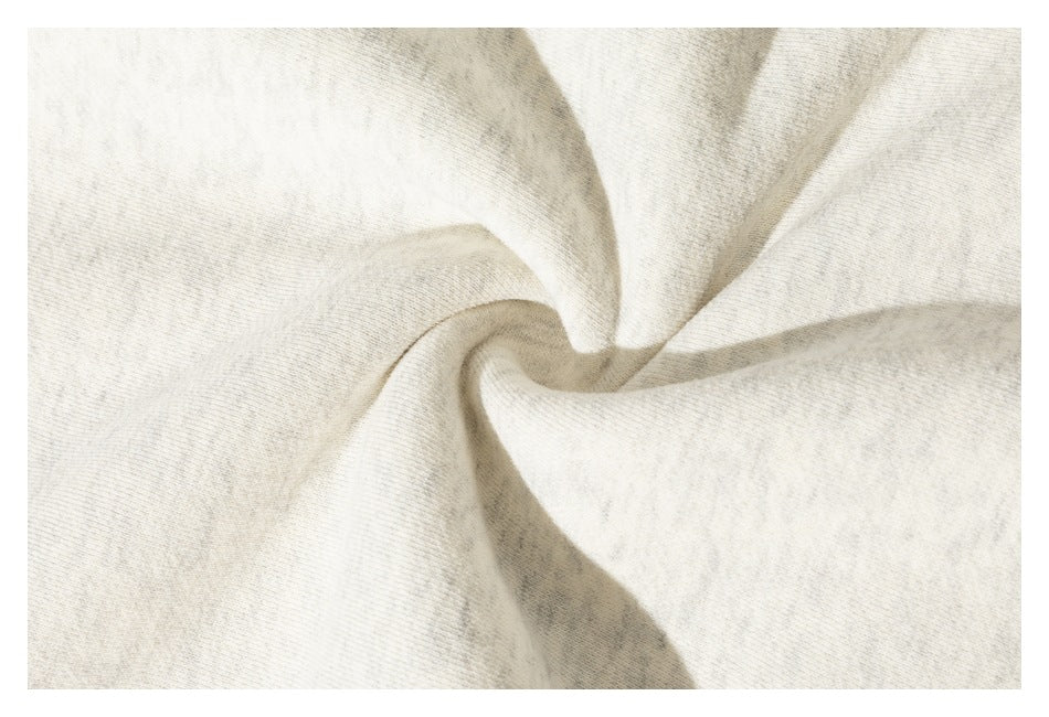 Close-up of softly folded, lightly heathered cream garment fabric.