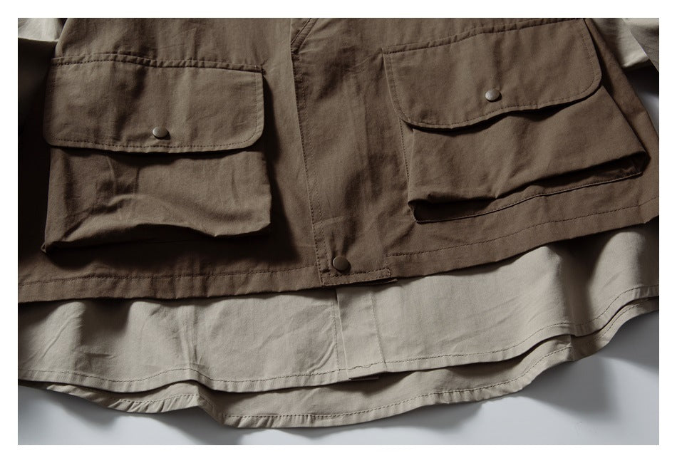 Close-up of a brown overshirt with large flap pockets and a light beige layer visible beneath the hem.