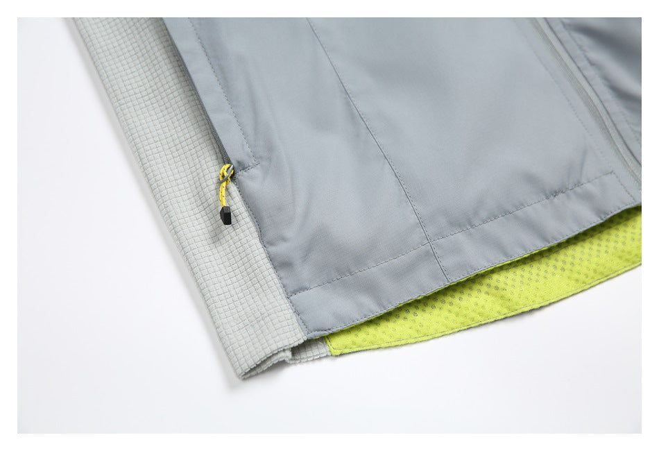 Close-up of the gray jacket's lower pocket, yellow zipper pull, textured side panel, and lime lining.