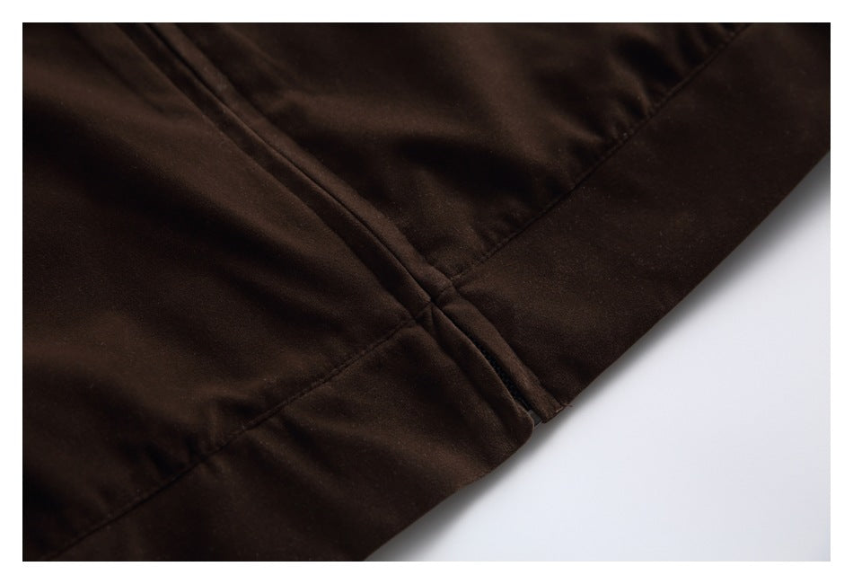 Close-up of dark brown garment fabric with intersecting stitched seams and a folded edge.