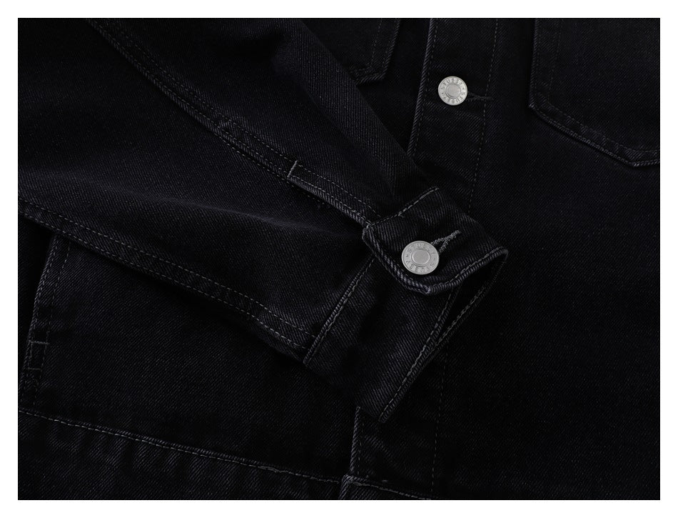 Black denim jacket sleeve cuff folded across the front, showing a silver snap button.