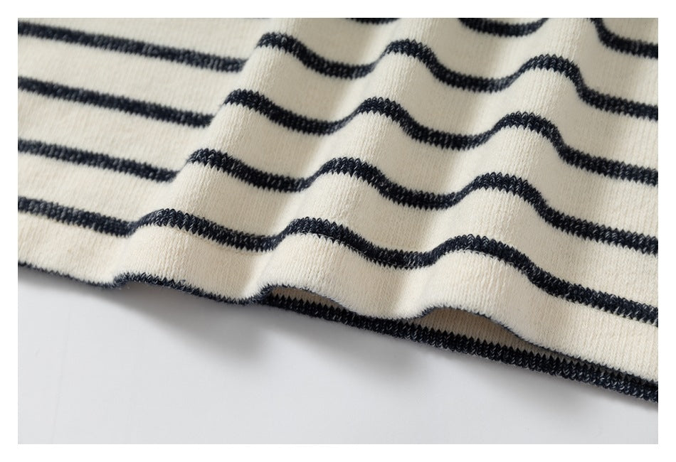 Close-up of cream knit fabric with narrow black horizontal stripes and a finished edge.