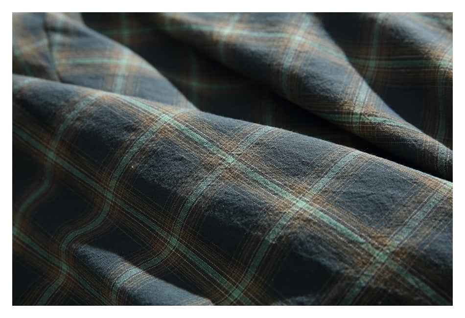 Extreme close-up of dark green, navy, and tan plaid fabric with a softly textured surface.