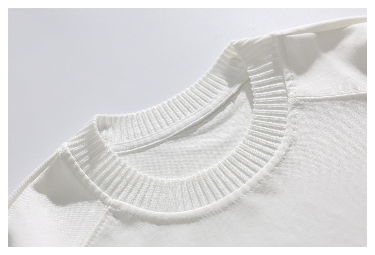 Close-up of a white T-shirt's wide ribbed crew neckline and shoulder stitching.