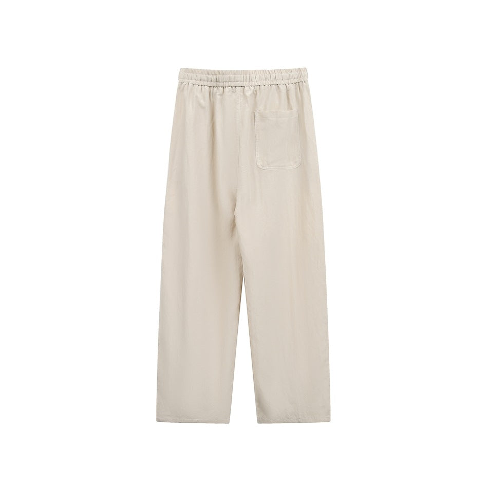 Back view of beige relaxed pants with an elastic waistband and a single patch pocket.