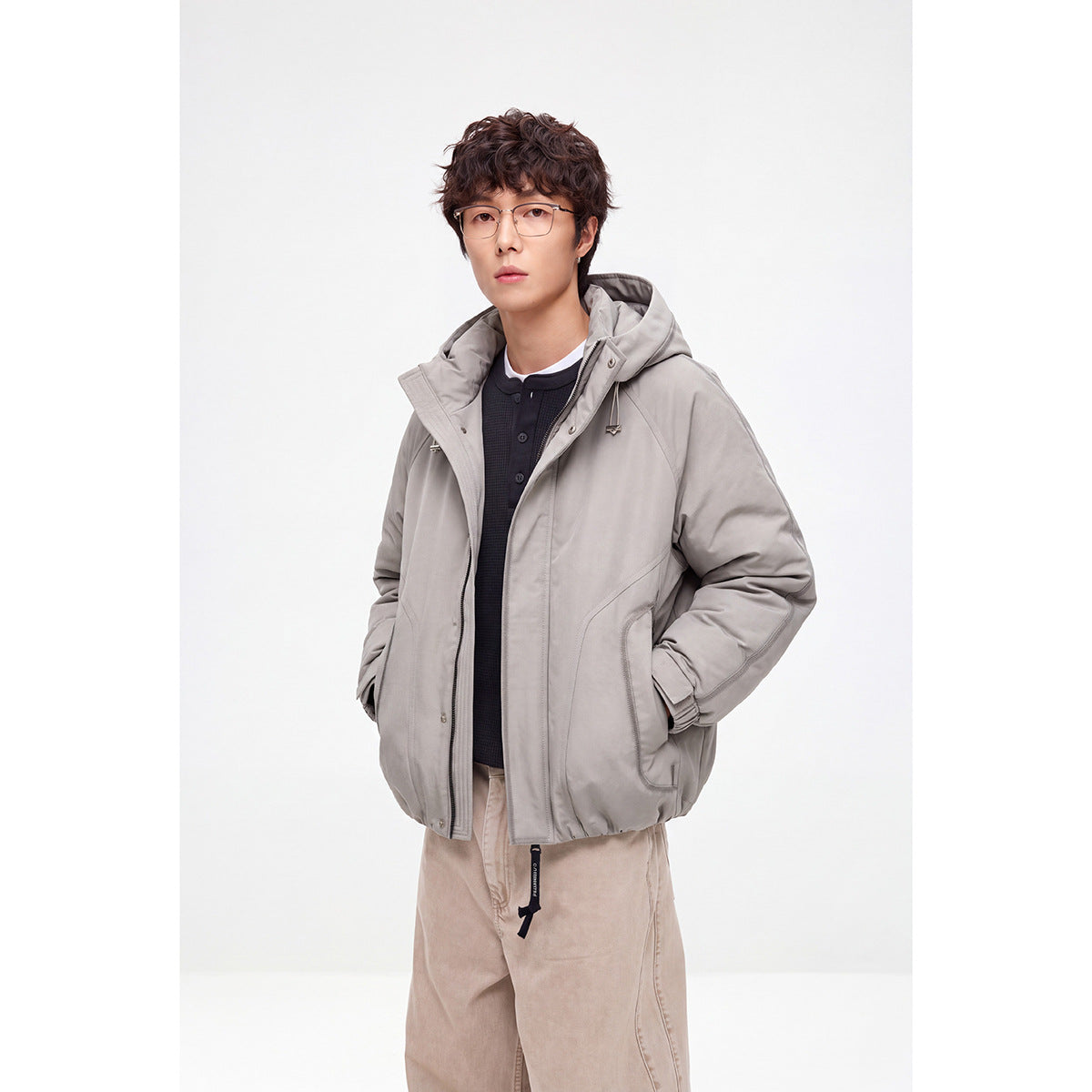 Model wearing a light gray hooded jacket with a front zipper, drawstrings, and large pockets.