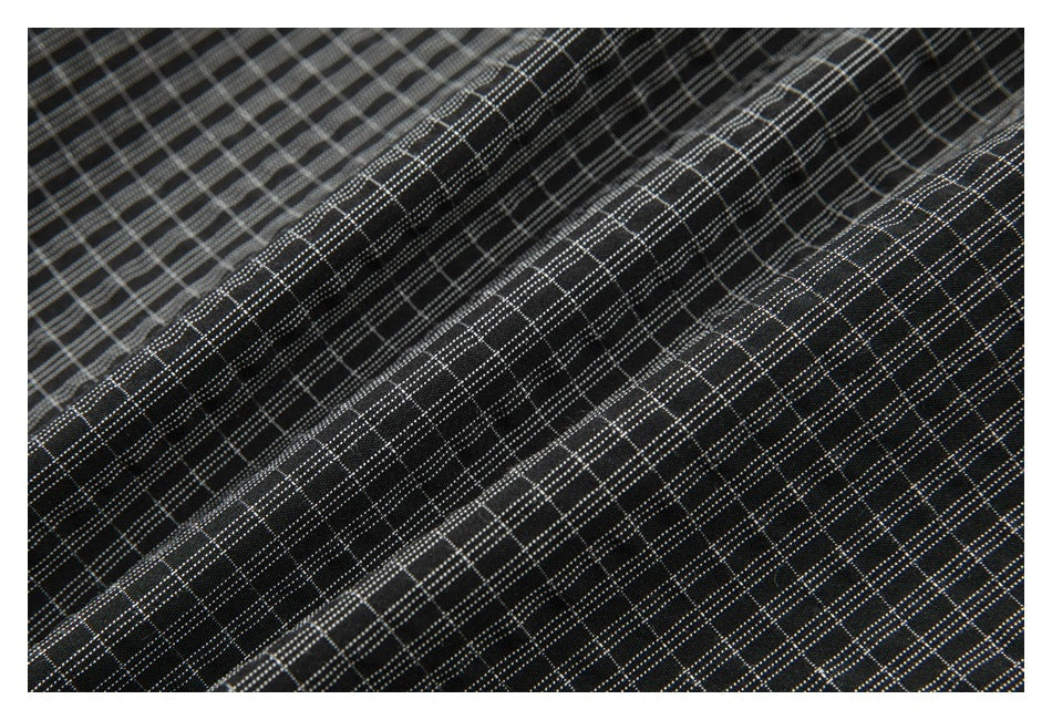 Macro view of black fabric with a fine gray windowpane check pattern and visible folds.