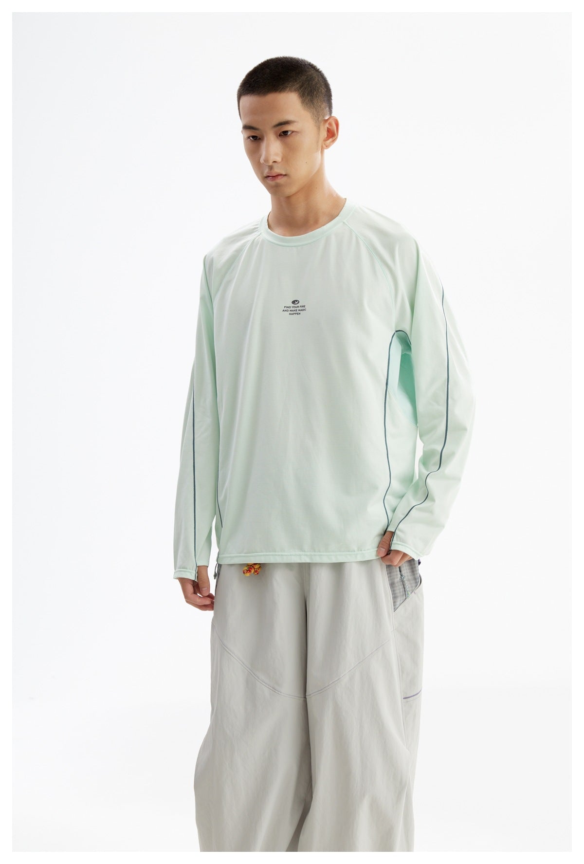 Man modeling a pale mint long-sleeve shirt with dark curved piping, shown from the front with light-gray trousers.