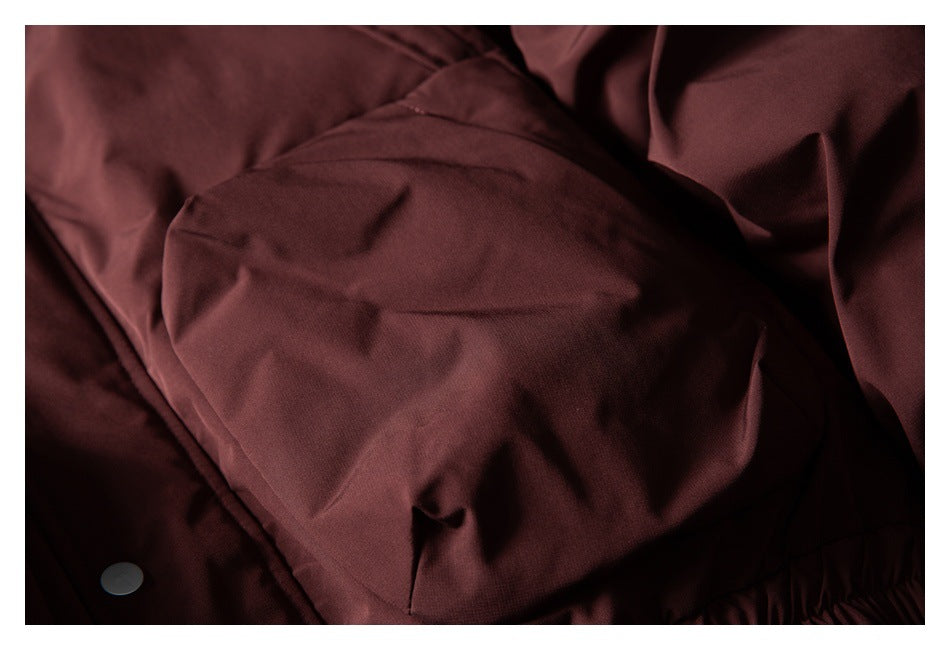 Close-up of a burgundy jacket pocket panel and a silver snap button.