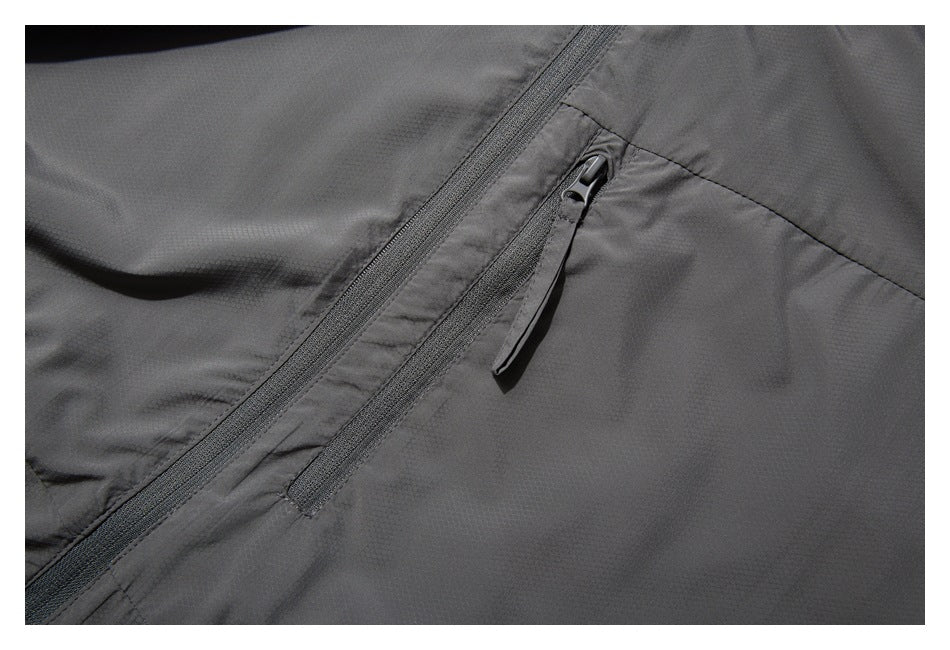 Close-up of a gray jacket's diagonal front zipper and a separate zip pocket with a long pull tab.