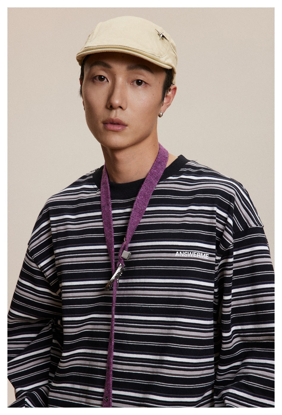 Close-up of a model wearing a black long-sleeve shirt with thin white and gray stripes and small chest lettering.