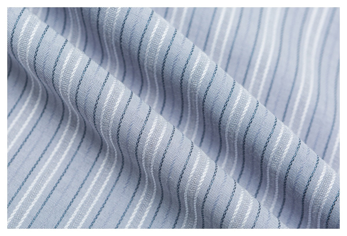 Macro view of pale blue shirt fabric with fine white and dark blue stripes, draped to show its texture.
