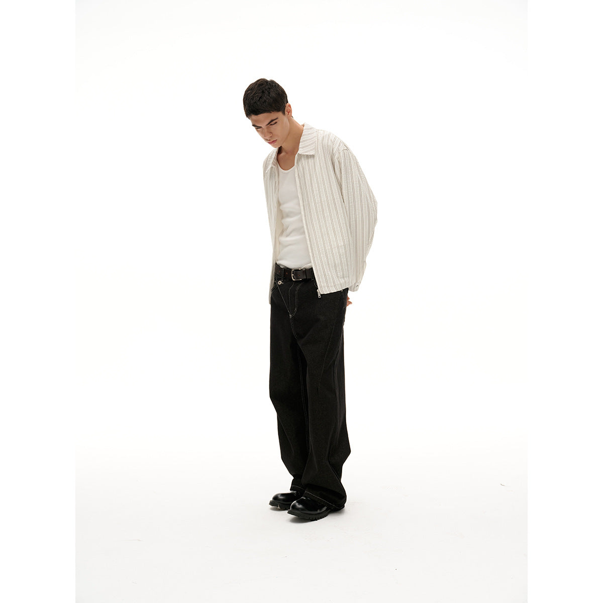 Full-length view of a model wearing an open cream striped shirt over a white tank and wide black trousers.