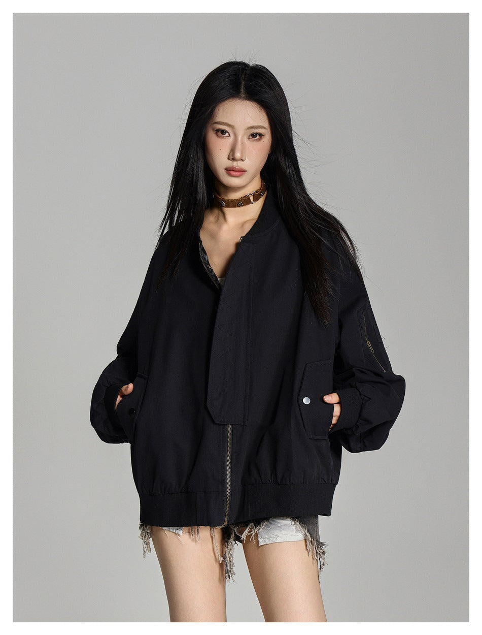 Model wearing an oversized black bomber jacket with snap pockets, ribbed hem, and a zippered sleeve pocket.