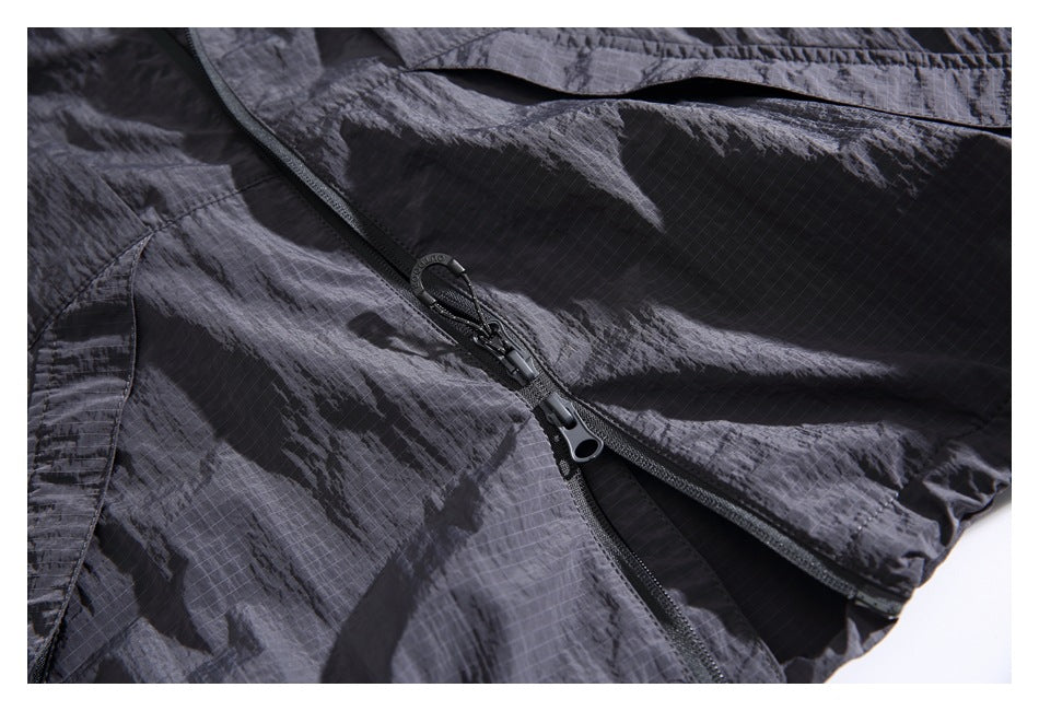 Close-up of a dark charcoal jacket’s front zipper, pull tabs and stitched ripstop fabric.