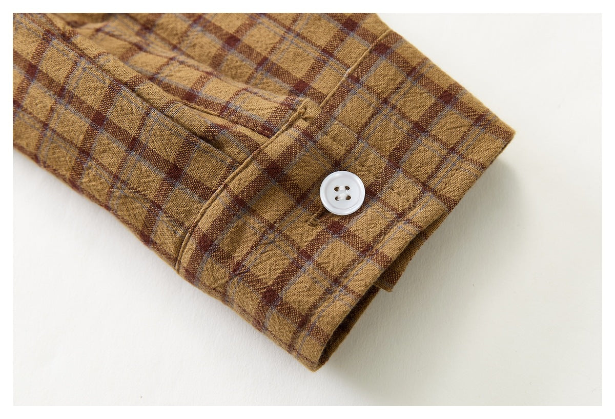 Close-up of a white button on the cuff of a mustard-brown plaid shirt.