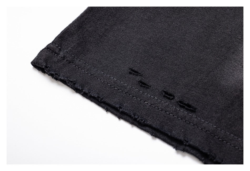 Close-up of a black garment hem with stitching and small distressed openings.
