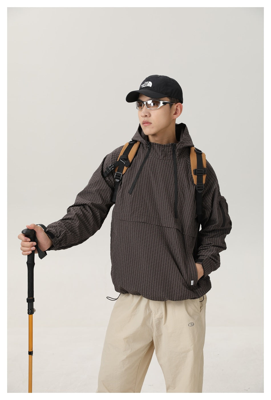 Front view of a model wearing a dark brown checked hooded pullover jacket with a large front pocket.